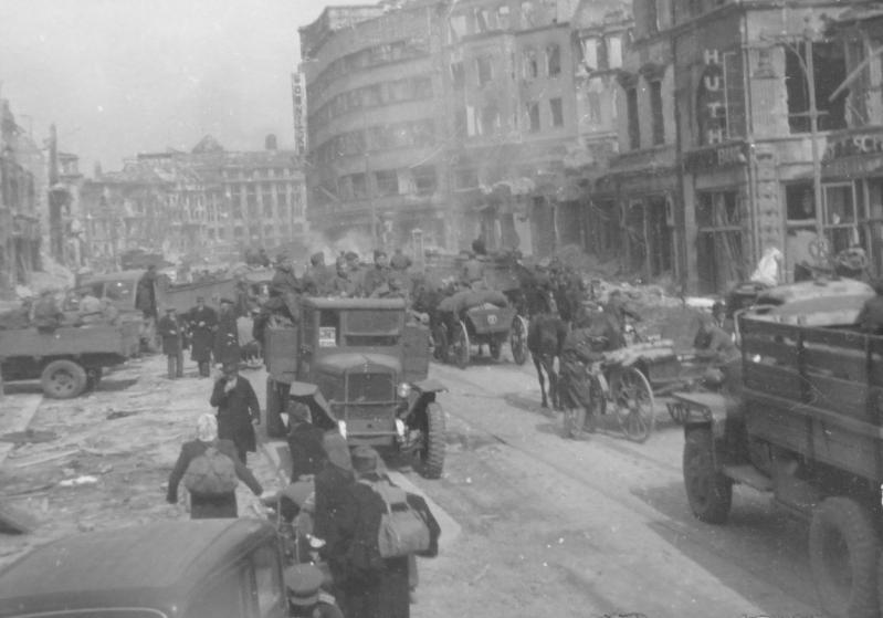 Советские автомобили и немецкие мирные жители на улице Берлина.<br />В центре фото – грузовой автомобиль ЗиС-5В