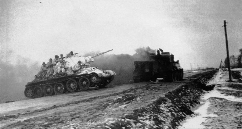 Cоветский танк Т-34-76 с десантом пересекает магистраль Житомир-Бердичев. Горящий немецкий танк «Тигр». 1-й Украинский фронт. Январь 1944