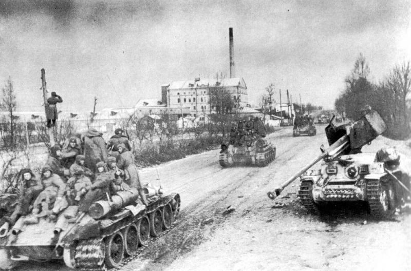 Советские танки Т-34 с пехотой на броне проезжают мимо подбитой немецкой САУ Marder III