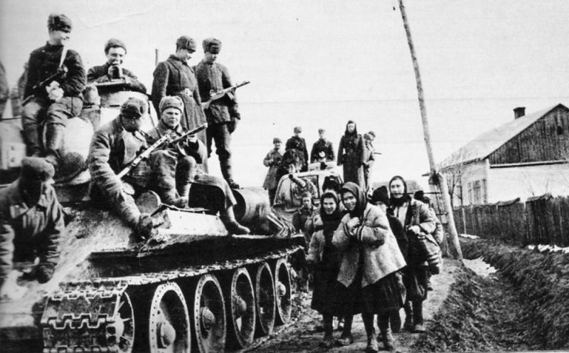 Танк Т-34 с солдатами на броне и мирные жители на улице украинского городка. Освобождение Украины. 1944