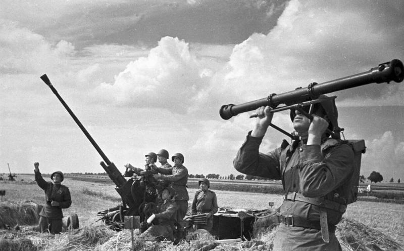 Расчет 37-мм зенитной пушки у аэродрома на Курском направлении. На переднем плане боец с высотомером. Август 1943
